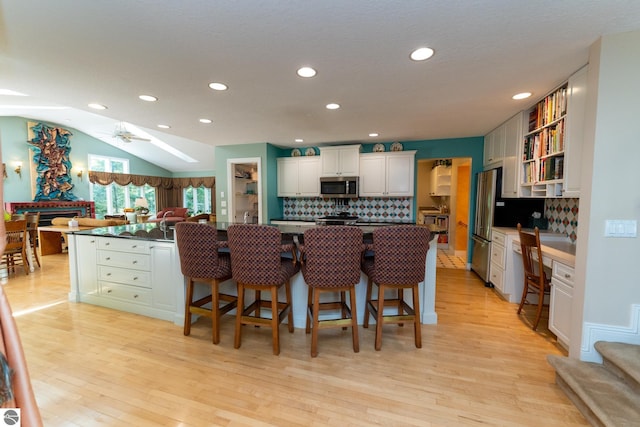 kitchen featuring stainless steel microwave, recessed lighting, tasteful backsplash, dark countertops, and light wood-type flooring