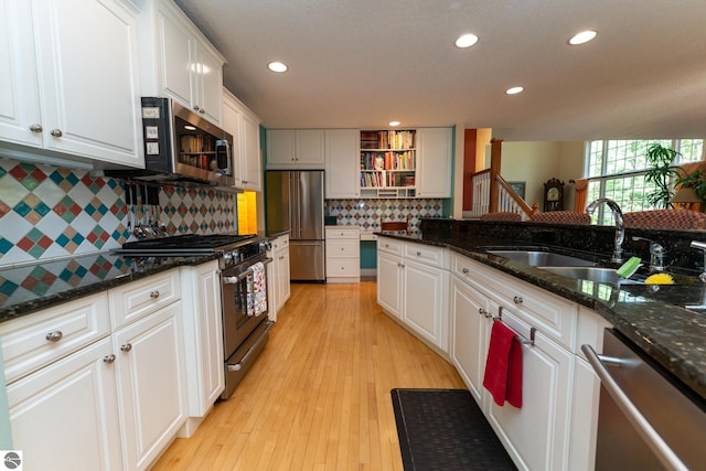 kitchen featuring appliances with stainless steel finishes, a sink, white cabinetry, backsplash, and recessed lighting