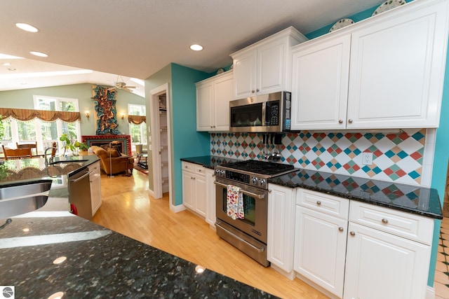 kitchen featuring stainless steel appliances, white cabinets, tasteful backsplash, light wood-style floors, and open floor plan