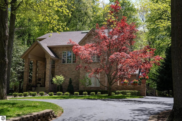 view of front of home with brick siding and roof with shingles