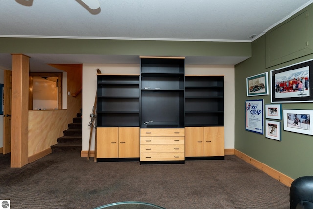 unfurnished living room featuring dark carpet, ornamental molding, baseboards, and stairway
