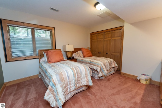 carpeted bedroom with a closet and baseboards