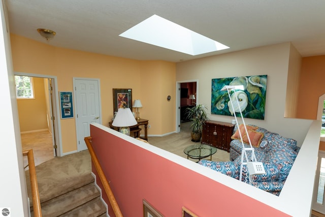 hall featuring a skylight, light colored carpet, and baseboards