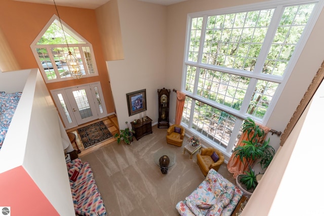 living area with a chandelier, a high ceiling, and carpet flooring