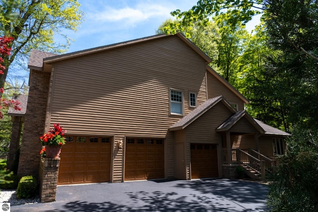 view of property exterior featuring a garage and asphalt driveway
