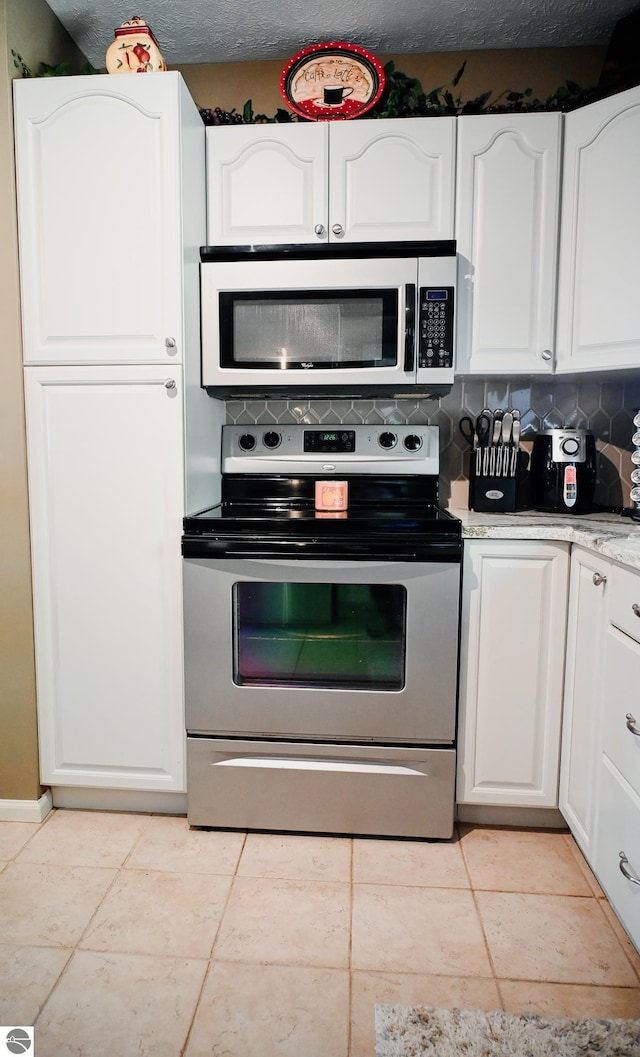 11255 E Fort Rd Unit H1, Suttons Bay, MI 49682 - kitchen with stainless steel range with electric cooktop, white cabinetry, tasteful backsplash, and light tile patterned flooring