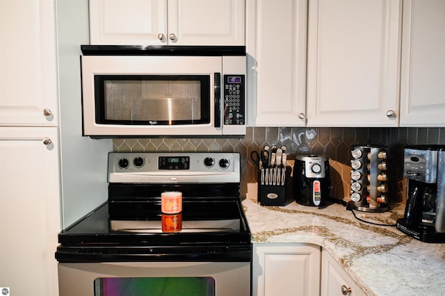 11255 E Fort Rd Unit H1, Suttons Bay, MI 49682 - kitchen with stainless steel electric stove, white cabinetry, and decorative backsplash