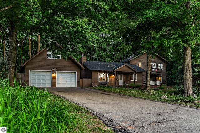 5540 Golf Meadows Dr, Bellaire, MI 49615 - rustic home featuring driveway, a chimney, and an attached garage
