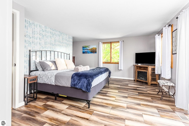 5540 Golf Meadows Dr, Bellaire, MI 49615 - bedroom with baseboards, an accent wall, wood finished floors, and wallpapered walls