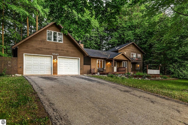 5540 Golf Meadows Dr, Bellaire, MI 49615 - chalet / cabin featuring driveway, a chimney, a porch, and an attached garage