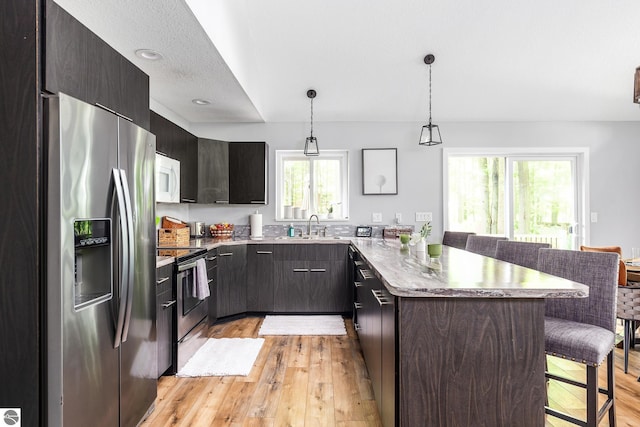 5540 Golf Meadows Dr, Bellaire, MI 49615 - kitchen featuring appliances with stainless steel finishes, a breakfast bar, light wood-type flooring, and a sink