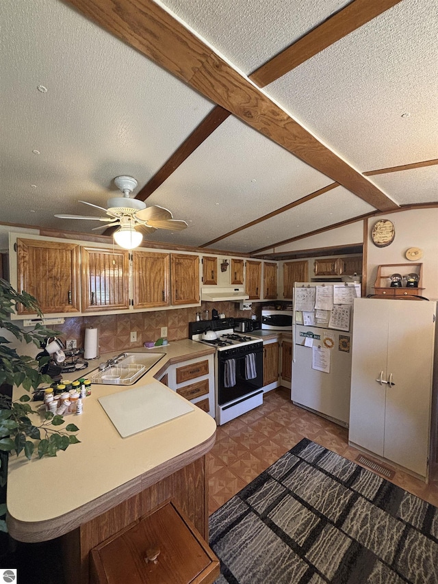 4505 Goldenrod Dr, Traverse City, MI 49685 - kitchen with gas range oven, freestanding refrigerator, a sink, a textured ceiling, and light countertops