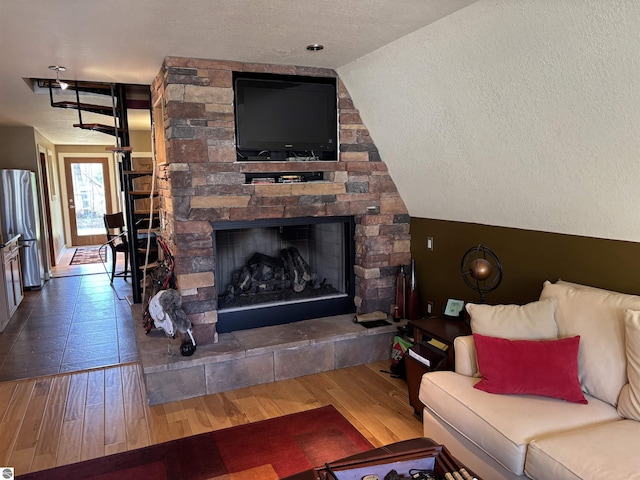 2050 Hiawatha Dr, Cadillac, MI 49601 - living room featuring a textured ceiling, wood finished floors, a fireplace, and lofted ceiling