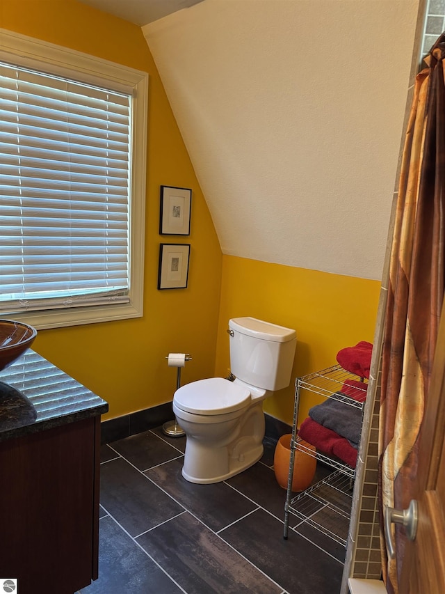 2050 Hiawatha Dr, Cadillac, MI 49601 - bathroom with lofted ceiling, toilet, tile patterned flooring, and vanity