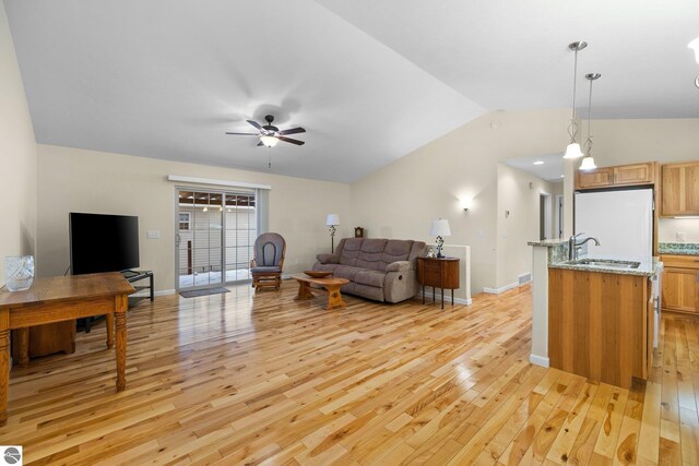 9803 Deer Track Ct, Interlochen, MI 49643 - living room featuring light wood-type flooring, vaulted ceiling, a ceiling fan, and baseboards