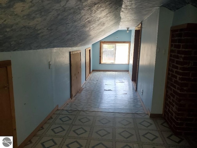 312 S Brown St, Edmore, MI 48829 - additional living space featuring light flooring, vaulted ceiling, baseboards, and a textured ceiling
