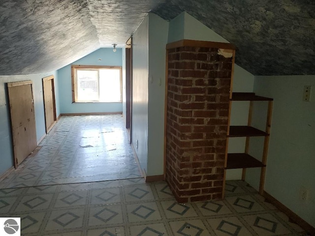 312 S Brown St, Edmore, MI 48829 - additional living space with a textured ceiling, vaulted ceiling, baseboards, and light floors