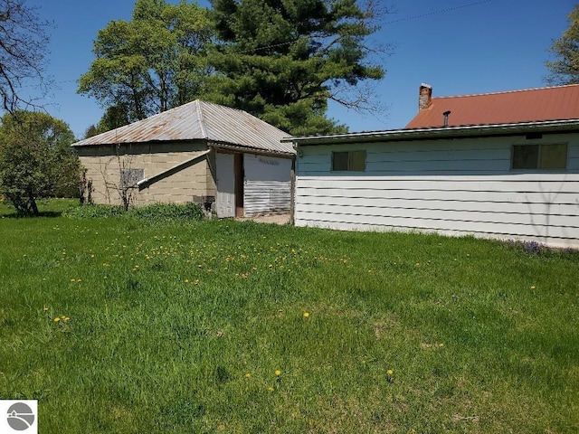 312 S Brown St, Edmore, MI 48829 - view of property exterior with a chimney, a yard, and metal roof