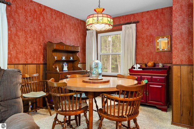 7548 S Dune Hwy, Empire, MI 49630 - dining area featuring wallpapered walls, a wainscoted wall, and light colored carpet