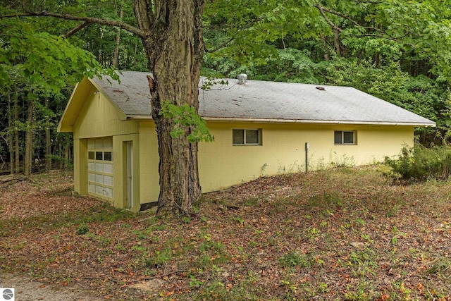 7548 S Dune Hwy, Empire, MI 49630 - view of property exterior featuring concrete block siding, a shingled roof, and a wooded view