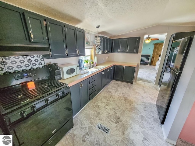 411 S Grover Ave Lot 39, Alma, MI 48801 - kitchen featuring gas stove, white microwave, vaulted ceiling, light countertops, and freestanding refrigerator