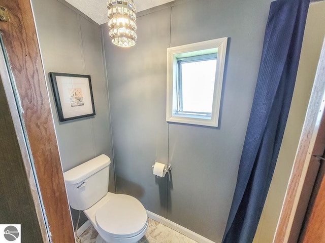 411 S Grover Ave Lot 39, Alma, MI 48801 - bathroom featuring toilet, baseboards, and a chandelier
