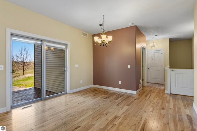 8233 Barney Rd, Traverse City, MI 49684 - unfurnished dining area with a chandelier, light wood-style flooring, and baseboards