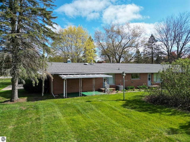 8670 E Pickard Rd, Mount Pleasant, MI 48858 - back of house featuring a patio, a yard, central AC unit, brick siding, and a shingled roof