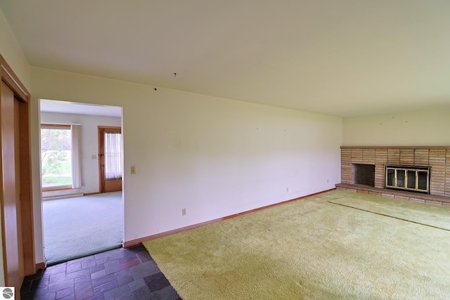 8670 E Pickard Rd, Mount Pleasant, MI 48858 - unfurnished living room with dark carpet, a fireplace, baseboards, and dark stone finish floors