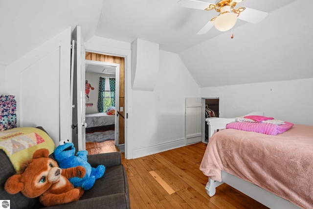 bedroom featuring light wood-type flooring, lofted ceiling, a ceiling fan, and baseboards