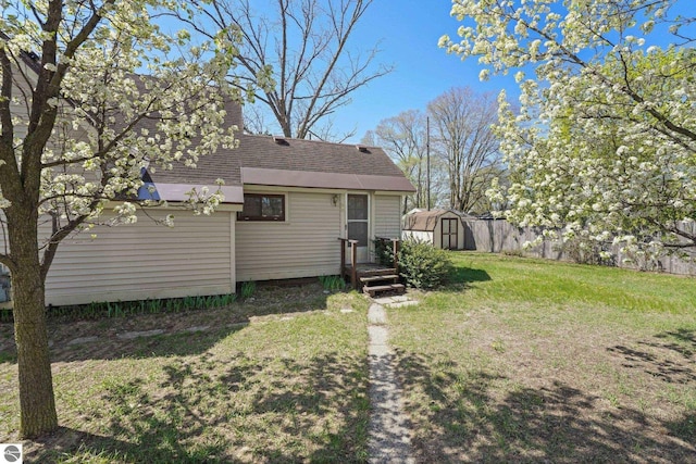 back of house featuring a shed, an outdoor structure, a shingled roof, and a chimney
