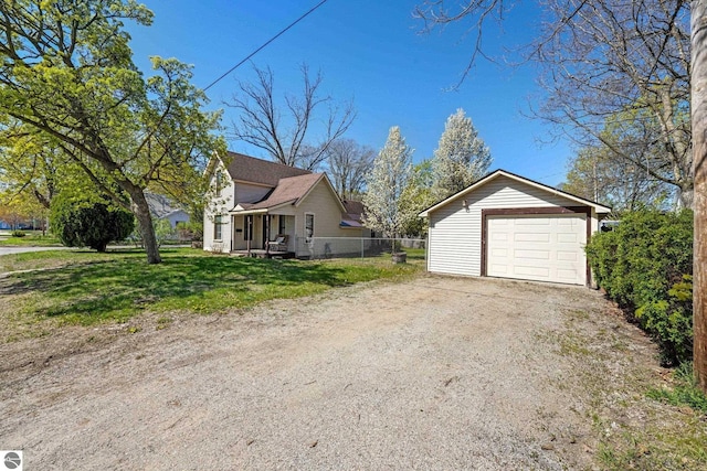 view of property exterior with an outbuilding, a detached garage, dirt driveway, and covered porch