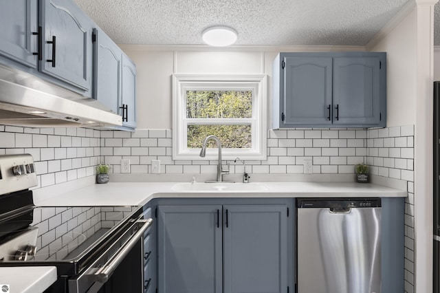 kitchen with stainless steel appliances, a sink, a textured ceiling, light countertops, and backsplash