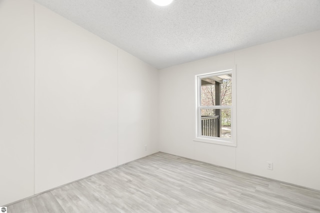 empty room with light wood-type flooring and a textured ceiling