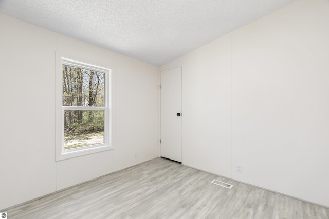 spare room featuring light wood finished floors and a textured ceiling