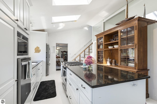 3121 Grace Rd, Frankfort, MI 49635 - kitchen with appliances with stainless steel finishes, a skylight, white cabinets, a center island, and dark stone counters