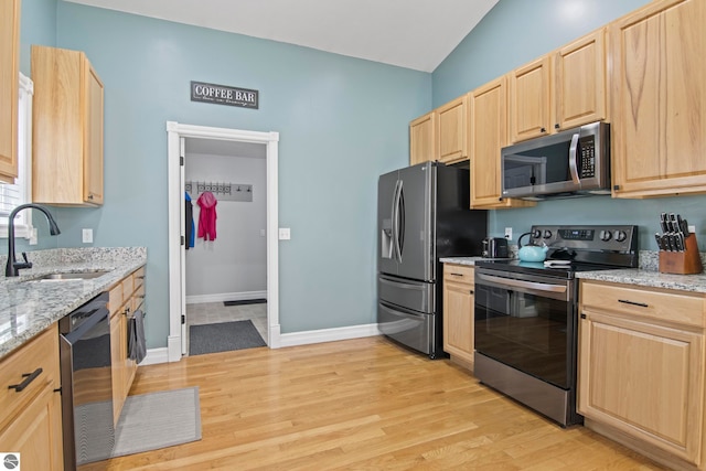 8256 Mapleleaf Dr, Traverse City, MI 49684 - kitchen with stainless steel appliances, light brown cabinets, a sink, light wood finished floors, and light stone countertops