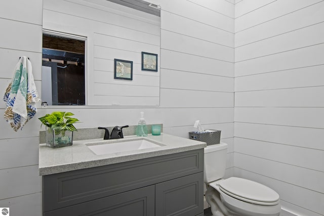 8256 Mapleleaf Dr, Traverse City, MI 49684 - bathroom with toilet, vanity, and wooden walls