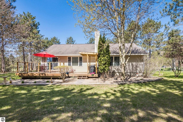8256 Mapleleaf Dr, Traverse City, MI 49684 - rear view of house with a wooden deck, a yard, a chimney, and a shingled roof