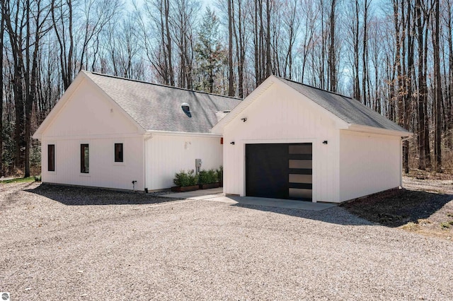 20651 E Trails End Trl, Interlochen, MI 49643 - view of front of house featuring gravel driveway, a shingled roof, and a garage