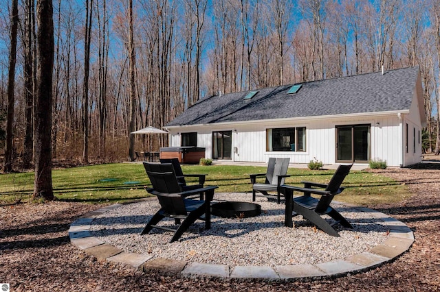 20651 E Trails End Trl, Interlochen, MI 49643 - rear view of house featuring a hot tub, an outdoor fire pit, a shingled roof, and a yard