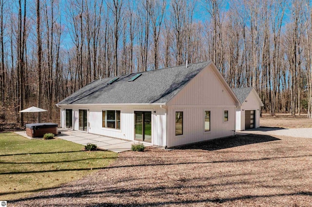20651 E Trails End Trl, Interlochen, MI 49643 - view of side of property with a hot tub, an attached garage, a shingled roof, driveway, and a yard