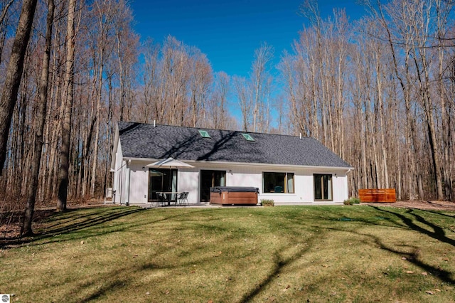 20651 E Trails End Trl, Interlochen, MI 49643 - rear view of property featuring a hot tub, a shingled roof, a lawn, and a patio area