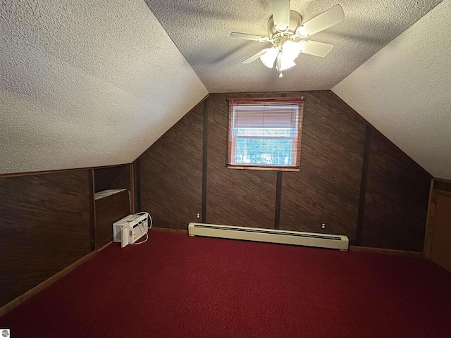 additional living space with baseboard heating, a textured ceiling, lofted ceiling, carpet flooring, and a ceiling fan