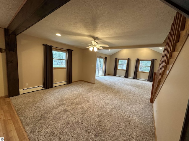 empty room with healthy amount of natural light, a ceiling fan, vaulted ceiling, a baseboard heating unit, and a textured ceiling