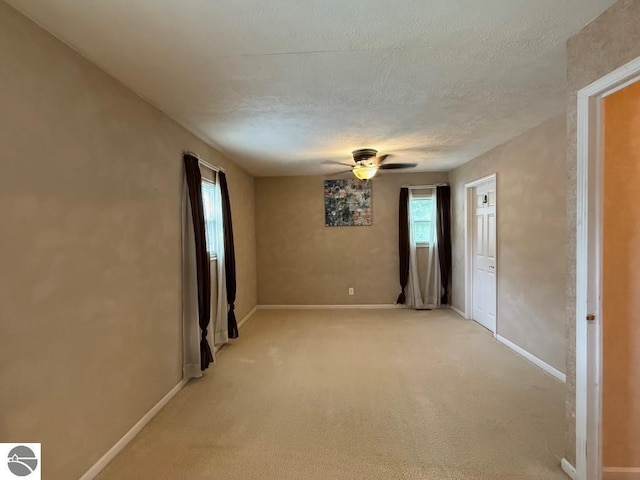 1411 N Dr, Mount Pleasant, MI 48858 - empty room featuring healthy amount of natural light, ceiling fan, baseboards, a textured ceiling, and light carpet