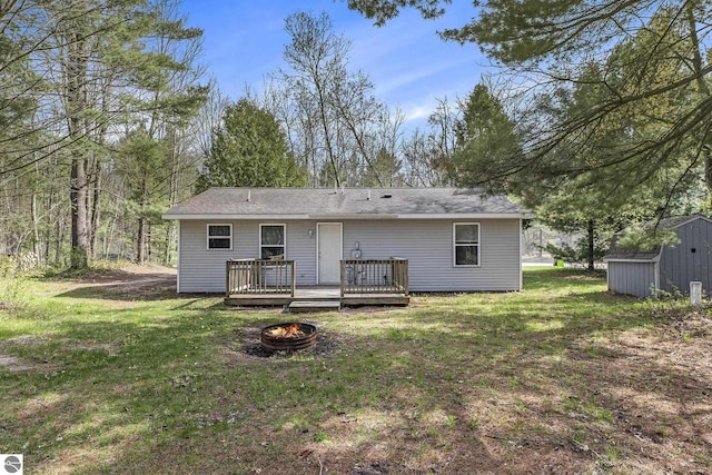 7401 Red Maple Dr, Cadillac, MI 49601 - rear view of property with a fire pit, a storage unit, a deck, a lawn, and an outdoor structure