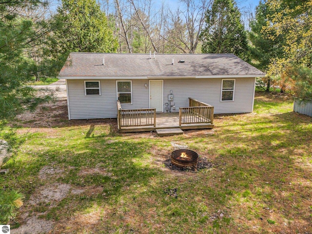 7401 Red Maple Dr, Cadillac, MI 49601 - back of house with an outdoor fire pit, a deck, and a yard