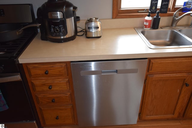 kitchen featuring dishwasher, gas stove, a sink, light countertops, and brown cabinets