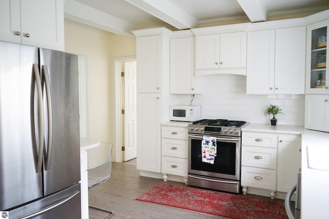 kitchen featuring stainless steel appliances, beam ceiling, wood finished floors, light countertops, and white cabinetry